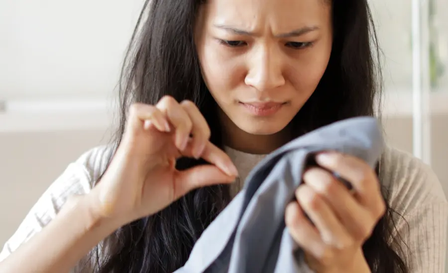 Mujer revisando una prenda con sospecha de infidelidad