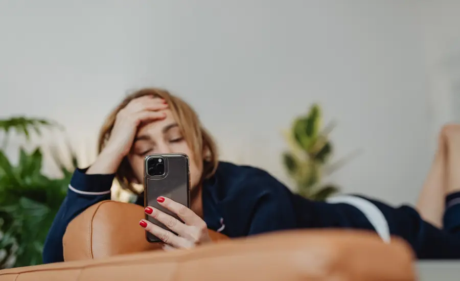 Mujer revisando el telefono en la etapa de negacion del duelo amoroso