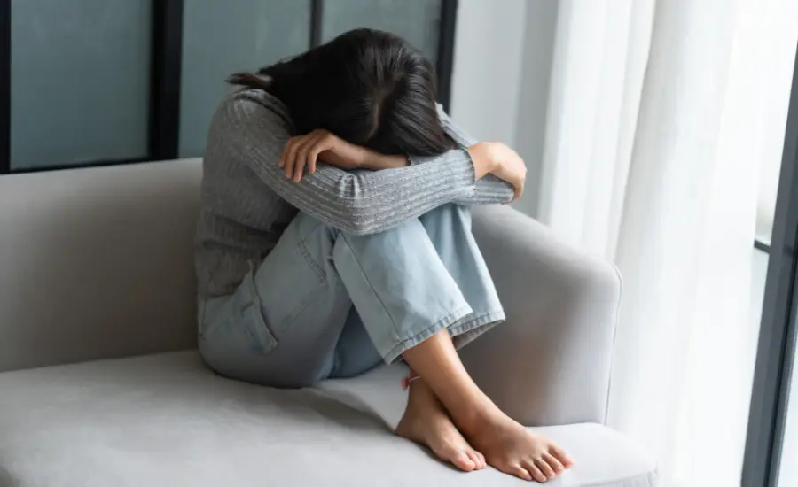 Mujer llorando encogida en un sillon en la etapa de tristeza del duelo