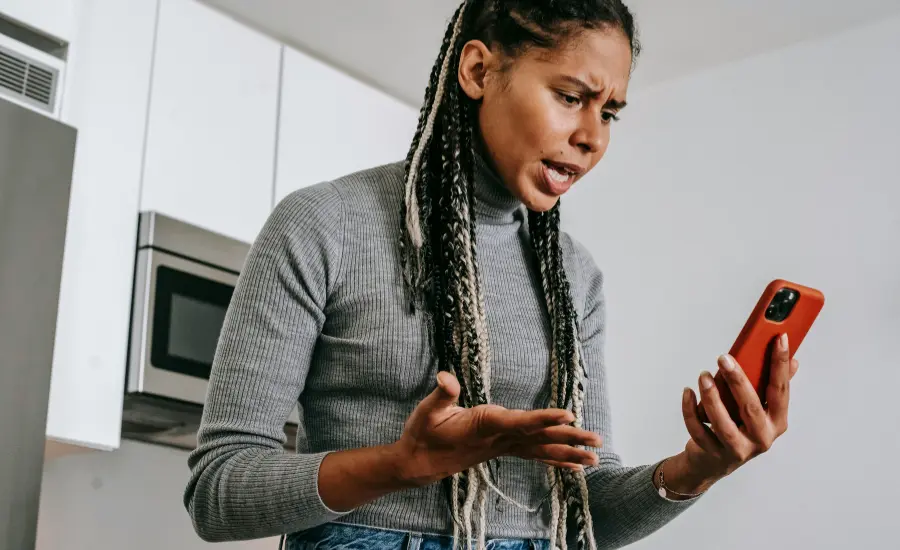 Mujer latina enojada viendo el celular en la cocina